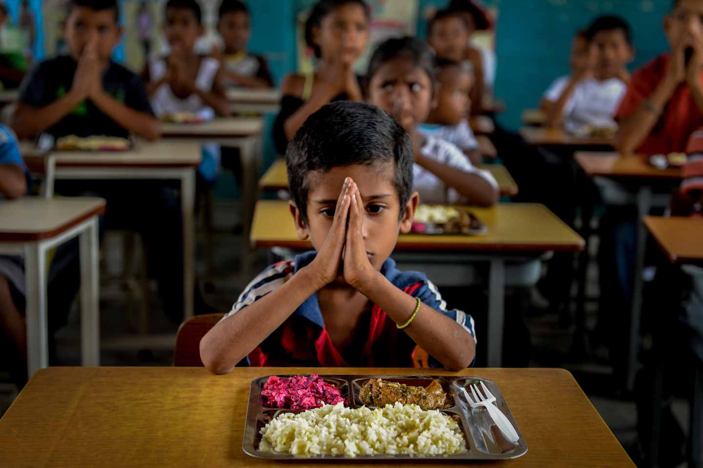 © Federico Parra. Children pray before eating at a shanty town in Higuerote, 117 km east of Caracas on August 26, 2016. As part of a volunteer program, thousands of Venezuelan children receive their school meals during holidays in an initiative to address food shortages affecting the country.