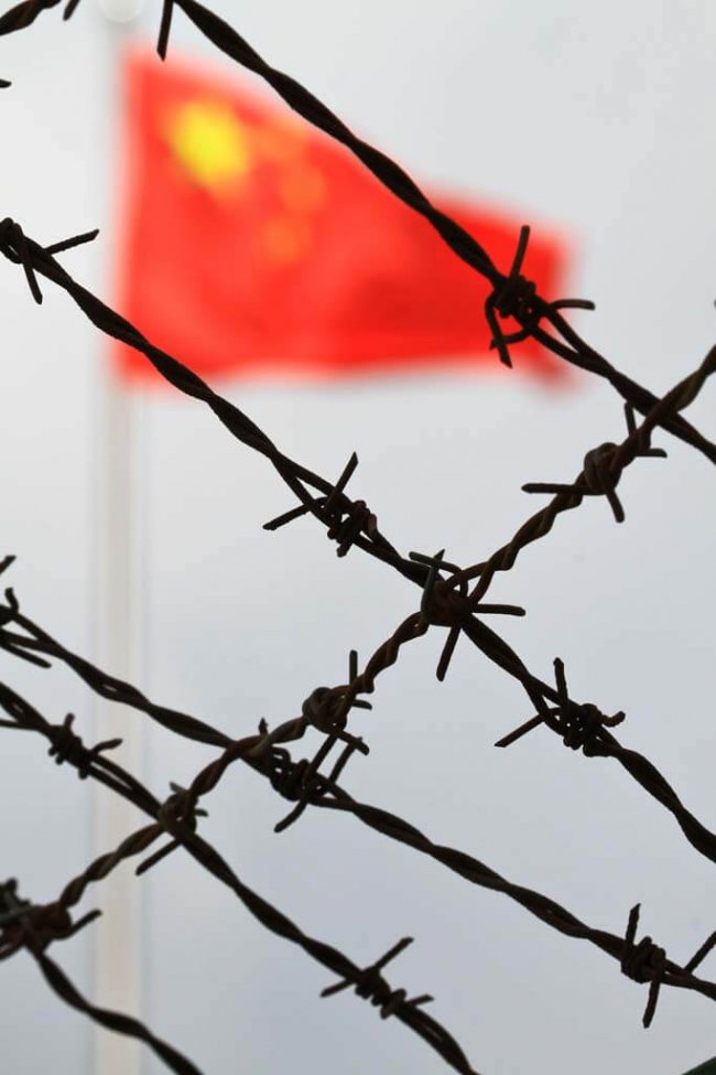 macau-photo-agency-vtHmsuXyEqM-unsplash The flag of China, also known as the Five-star Red Flag behind a barbed wire