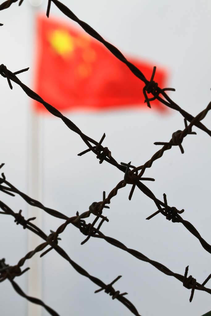 macau-photo-agency-vtHmsuXyEqM-unsplash The flag of China, also known as the Five-star Red Flag behind a barbed wire